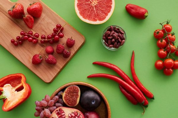 Top view of a vibrant selection of fruits and vegetables on a green background.