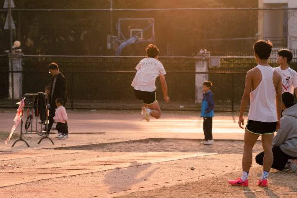 Teenagers enjoying outdoor activities in a school playground during sunset, showcasing energy and sportsmanship.